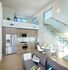 Contemporary apartment interior featuring an open kitchen with sleek wooden cabinetry, cozy dining area, modern staircase with glass railing, and inviting loft space.