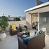 Inviting urban terrace with stylish wicker furniture, vibrant cushions, and a picturesque city view, perfect for relaxation and entertaining.
