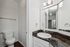 Bright and modern bathroom with sleek white cabinetry, elegant granite countertop, and large mirror under stylish lighting.