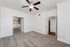 Bright and spacious bedroom with plush carpeting, elegant crown molding, and a modern ceiling fan, opening to a sunlit living area and stylish bathroom.