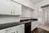 Modern kitchen with sleek black countertops, white cabinetry, and open view to sunlit living room.