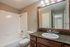 Modern bathroom with granite countertop, elegant mirror, and spotless white tiles for a sleek finish.