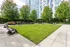 Vibrant outdoor common area with lush green lawn, stylish seating, and shaded gazebo amidst modern high-rise setting.