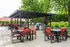 Elegant outdoor patio with modern pergola, vibrant seating, and built-in grills, surrounded by lush greenery.