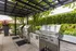 Chic outdoor barbecue area with stainless steel grills set amidst lush greenery and modern pergola.