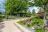 Lush garden view with vibrant greenery and colorful flowers, featuring a modern outdoor seating area under shady pergolas with red umbrellas, creating a tranquil retreat.