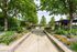 Elegant outdoor patio with lush greenery, vibrant flowers, and cozy seating under bright umbrellas, creating a tranquil relaxation space.