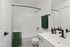 Modern bathroom with sleek fixtures, elegant green and white accents, and a pristine tub and shower combination.
