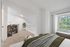Bright, open loft bedroom with plush carpeting, elegant wooden shelving, and a large window offering lush green views.