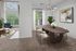 Elegant dining area with modern chandelier, surrounded by large windows and natural light, blending seamlessly into a cozy living space with chic furniture and lush greenery views.