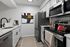 Modern kitchen with sleek appliances, elegant white cabinetry, and stylish countertop accented by contemporary art.