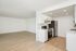 Contemporary open-plan apartment showcasing a sleek kitchen with modern appliances and a spacious living area with stylish wood flooring.