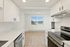 Bright, modern kitchen with sleek white cabinets, stainless steel appliances, and large window offering stunning views.