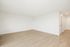 Bright and airy empty room with sleek wooden flooring and white walls, perfect for personal styling and design.