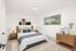 Bright and welcoming bedroom with modern decor, featuring a cozy bed, stylish bedside tables, and large window with lush garden view.