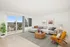 Bright and spacious living room with elegant decor, featuring a cozy gray sectional sofa, stylish wooden accents, and a sunny balcony with breathtaking views.