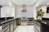 Modern kitchen with sleek black countertops, stainless steel appliances, and elegant tile backsplash, perfect for culinary enthusiasts.