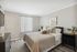 Elegant bedroom featuring a cozy bed with plush pillows, chic decor, and abundant natural light through sheer curtains.