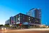 Modern urban apartment complex with sleek architecture, featuring expansive windows and city street views at dusk.
