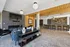 Modern open-concept living space with elegant seating, sleek TV setup, and a chic kitchen with bar seating under stylish lighting.