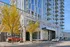 Modern high-rise apartment building with sleek glass facade, showcasing balconies and vibrant autumn trees, offering urban living elegance.