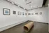 Contemporary art gallery corner showcasing diverse framed artworks in a sleek, minimalist setting with polished concrete floors.