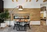 Modern apartment lounge featuring a cozy table setting with chairs, elegant fireplace, stylish wood paneling, and ambient lighting.