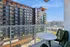 Sophisticated city view from a modern balcony with stylish seating, overlooking contemporary apartment buildings.