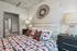Chic bedroom interior showcasing a stylish bed with patterned bedding, modern lamps, and decorative wall art, leading to a spacious walk-in closet and bathroom.