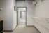 Modern walk-in closet with ample shelving leading to a chic bathroom with elegant floor tiles and a stylish shower curtain.