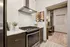 Modern kitchen with sleek stainless steel appliances, elegant wooden cabinetry, and cozy workspace accented by artistic wall decor.