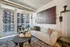 Modern apartment living room with stylish decor, featuring a cozy sofa, chic wall art, and expansive floor-to-ceiling windows overlooking a cityscape.