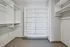 Spacious walk-in closet with sleek white shelving and ample hanging space, ideal for organized living.