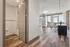 Modern apartment with sleek wooden floors, an open living space, and stunning city views through large windows.