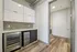 Modern kitchen nook with sleek cabinetry, stainless steel appliances, and elegant wood flooring adjacent to a convenient laundry room.
