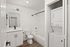 Modern bathroom featuring sleek design with a white vanity, bathtub, and convenient in-unit stacked washer and dryer.
