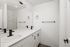 Bright and modern bathroom with elegant double sinks, sleek black fixtures, and expansive mirror highlighting minimalist design.