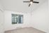 Bright bedroom with a modern ceiling fan, plush carpeting, and a large window offering a scenic view.