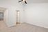 Bright, airy room with plush carpet, modern ceiling fan, and doors leading to additional spaces.