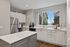 Bright and modern kitchen with sleek white cabinetry, stainless steel appliances, and a wide window offering natural light.