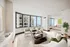 Elegant living area at ReNew Waterside  with chic furniture, floor-to-ceiling windows showcasing stunning city and lake views, seamlessly connected to a cozy bedroom.