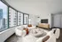 Modern living room at ReNew Waterside with large curved windows, plush white sofas, and a sleek entertainment center, offering a bright and inviting urban view.