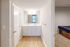 Bright and modern bathroom featuring dual sinks, elegant fixtures, and a large mirror, adjacent to a comfortable bedroom.