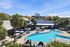 Inviting apartment community with a resort-style pool, lush palm trees, and ample sun loungers under a clear blue sky.