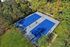 Aerial view of vibrant blue tennis courts surrounded by lush greenery, offering a serene recreational retreat.