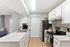 Modern kitchen with sleek white cabinets, stainless steel appliances, and a bright open layout leading into the living area.