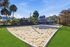 Inviting outdoor sand volleyball court surrounded by lush greenery and palm trees under a clear blue sky.