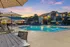 Inviting apartment complex with a sparkling swimming pool, surrounded by lush palm trees and elegant outdoor seating at sunset.