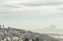 Breathtaking view of a picturesque cityscape nestled among vibrant autumn foliage, set against the majestic backdrop of a snow-capped mountain and serene sky.