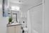 Sleek bathroom featuring modern fixtures, elegant granite countertop, and discreet in-unit laundry for convenience.